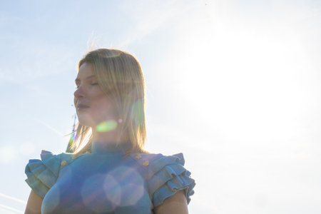 This is a tranquil portrait of a young Caucasian woman in profile, basking in the gentle glow of the...