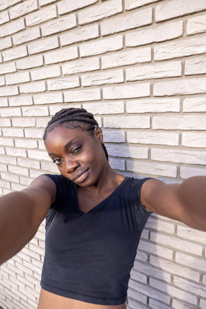 This is an intimate selfie of a young African woman with braided hair, featuring a playful smirk as...