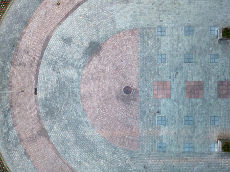An aerial view showcases a detailed stone pathway with both circular and square patterns in a public urban spaceの写真素材