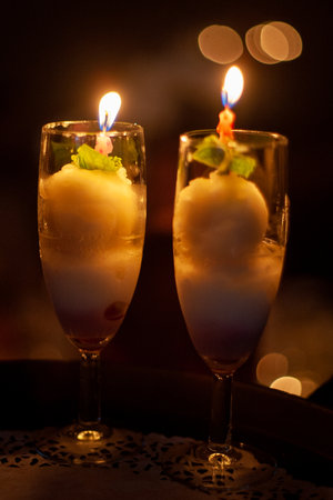 Elegant romantic dessert with ice cream, candles, and mint leaves in champagne glasses. Perfect for special occasions.の写真素材