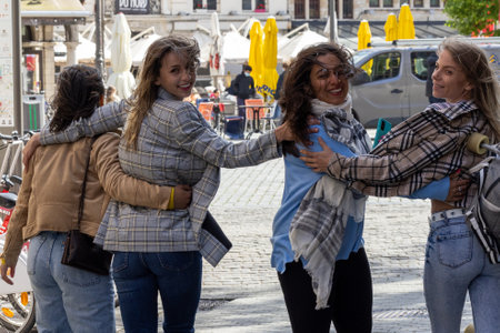 A group of four women enjoying a sunny day together, hugging and filled with laughter and joy in a...