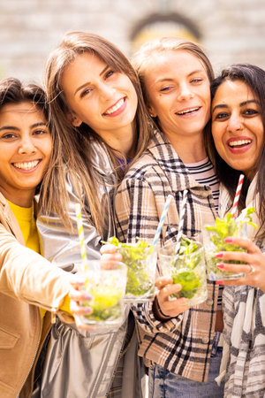 A diverse group of friends in a park, joyfully celebrating with drinks, representing happiness and...
