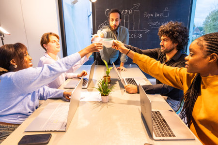 A diverse group of business professionals are celebrating and toasting during a meeting in a modern office environmentの写真素材