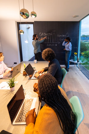 Group of business professionals in a modern office having a discussion with a presentation on a blackboard.の写真素材