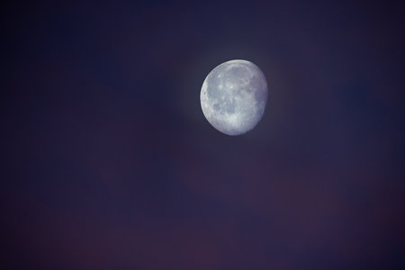 A stunning and beautiful view of the moon, surrounded by soft twilight hues in the evening sky above