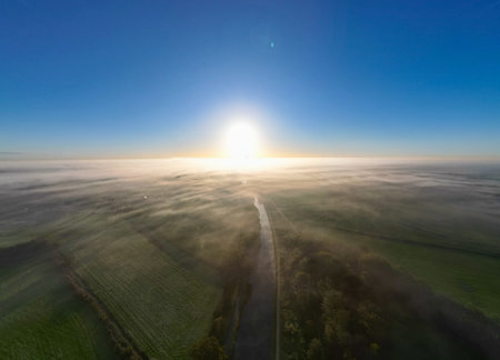 A breathtaking and stunning aerial view of a magnificent sunrise illuminating a tranquil and serene foggy landscapeの写真素材