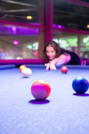 A focused player is getting ready to take an impressive shot at a vibrant pool table featuring colorful ballsの写真素材