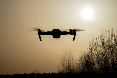A drone captured soaring against a beautiful sunset, showcasing the blend of modern technology and...