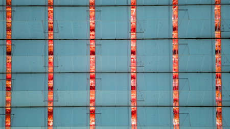 This image captures the rhythmic beauty of a modern greenhouses grow light system. The vertical lines of radiant red lights slice through the tranquil blue of the greenhouse panels, creating a striking pattern that exemplifies the marriage of industrial design and agricultural function. Industrial Elegance: The Rhythmic Pattern of Grow Lights in a Modern Greenhouse. High quality photoの写真素材