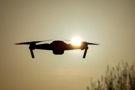 A stunning drone gracefully flying under the vibrant hues of a sunset, highlighting the beauty of...