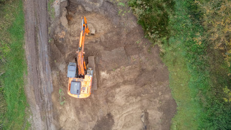 An excavator actively digging soil in a lush green area, effectively showcasing heavy machinery in actionの写真素材
