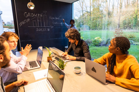 Business team in glasswalled room analyzing growth charts, brainstorming strategies, and discussing analysisの写真素材