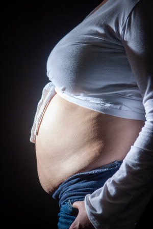A beautiful profile shot of a radiant pregnant woman embracing her baby bump, captured in lovely natural lightの写真素材