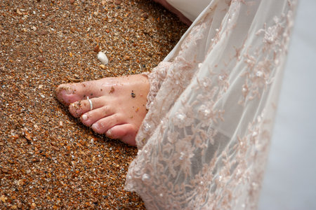 A stunning brides foot gracefully positioned on a sandy beach, capturing a moment of elegance and pure serenityの写真素材