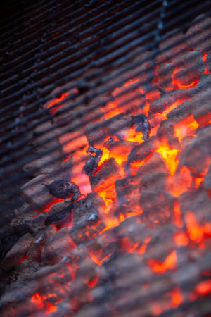 A closeup shot highlighting the glowing pieces of charcoal in a grill, ideal for barbecue and culinary cookingの写真素材