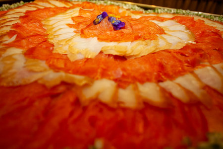 A brightly colored, vibrant salmon carpaccio, elegantly garnished with edible flowers, ideal for culinary presentationsの写真素材