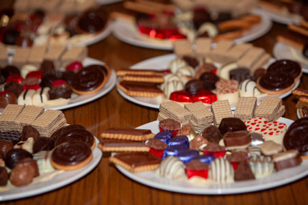 An irresistible and visually appealing display of chocolates, wafers, and assorted sweets artfully arranged on platesの写真素材
