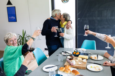 A vibrant celebration filled with love and camaraderie at a table with delicious food and fine wineの写真素材