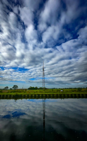 A tall pole reflects in the calm waters beneath a dramatic skyの写真素材