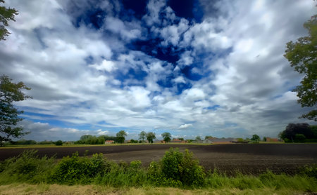 A stunningly picturesque view of a charming rural field beneath a captivating sky showcasing dynamic cloud patternsの写真素材