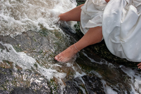 A brides feet are playfully immersed in sparkling water, beautifully capturing the essence of love and natureの写真素材