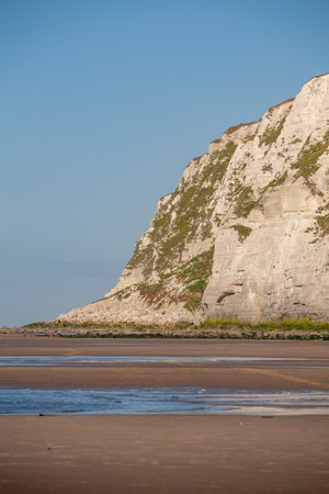 A stunning and breathtaking view of coastal cliffs paired with smooth golden sands beneath a brilliantly bright skyの写真素材