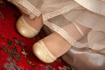 Delicate ballet flats elegantly peek out from underneath a stunning white dress that rests on a vibrant rugの写真素材