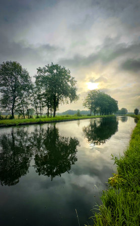 A serene and tranquil riverside view beautifully capturing the calm reflection of lush trees in the still watersの写真素材