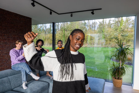 Group of friends dancing and having fun in a modern living room with a beautiful nature view in the background.の写真素材