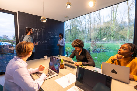 A team brainstorming project ideas in a modern office with large windows offering a serene nature view.の写真素材