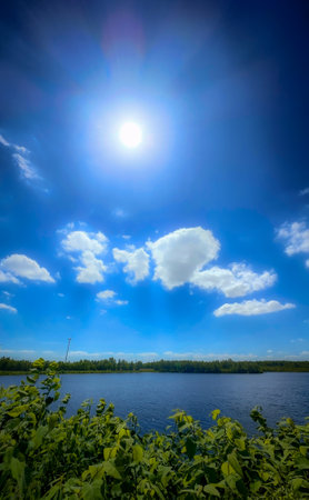 There is a breathtakingly stunning view showcasing a bright blue sky adorned with fluffy clouds reflected in calm waterの写真素材