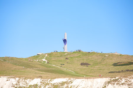 A monument stands tall on a hill under a clear blue sky, attracting many visitors eager for adventureの写真素材