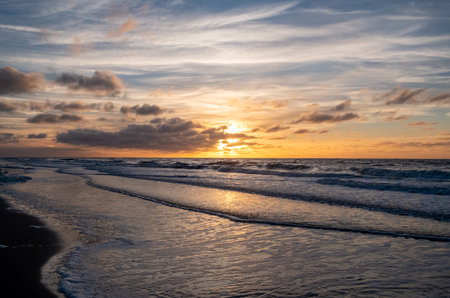 A stunningly beautiful sunset glows and reflects on the ocean waves, creating a peaceful beach atmosphereの写真素材