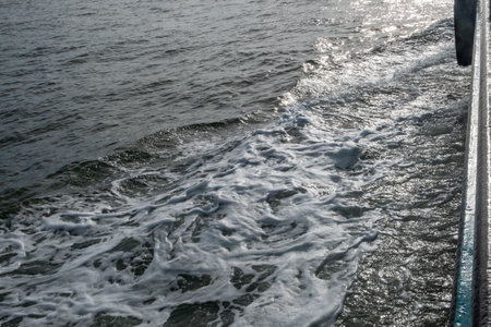 A serene and tranquil scene where gentle water waves create beautiful white foam under warm sunlightの写真素材
