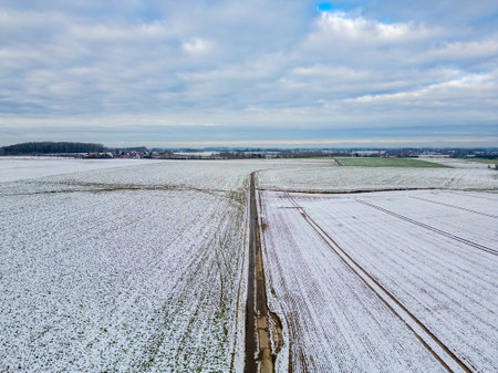 From an aerial perspective, vast snowy fields stretch beneath a cloudy sky, highlighting the stunning beauty of winterの写真素材