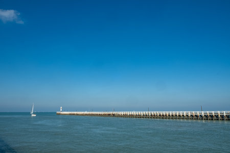 Tranquil view of a pier with sailing boats on calm waters under a blue skyの写真素材