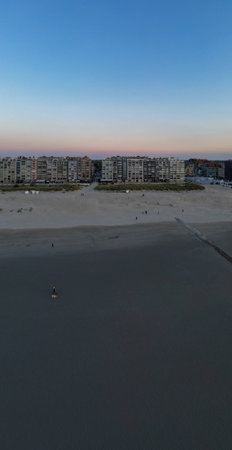 A beautiful and serene beach scene at dawn, showcasing coastal buildings in the background along with the horizonの写真素材
