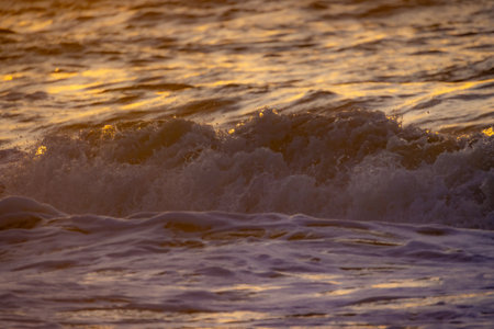 A serene view of ocean waves illuminated by warm sunset hues, showcasing natures incredible beautyの写真素材