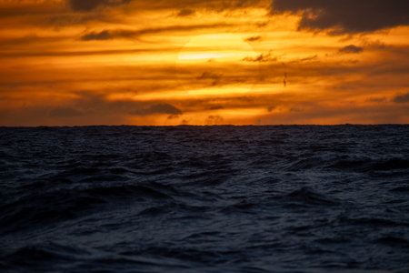 A tranquil sunset beautifully casts vibrant colors over gentle ocean waves, creating a truly breathtaking seascapeの写真素材