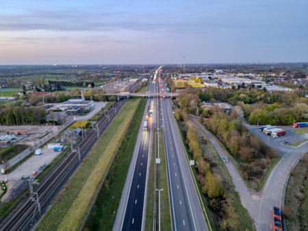 E19 Breda-Antwerp, Brecht, Antwerp, Belgium, April 8th, 2025, A breathtaking aerial photograph presents a busy highway surrounded by lush greenery and adjacent industrial zonesの写真素材