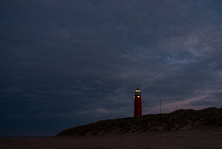 Eierland, De Cocksdorp, Texel, The Netherlands, Oktober 28th, 2024, A tranquil lighthouse stands brightly illuminated against a beautifully darkening evening sky as dusk fallsの写真素材