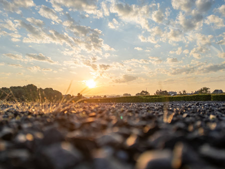 A stunning and beautiful sunset casts a warm golden light over a pebbled landscape, creating a truly serene atmosphereの写真素材
