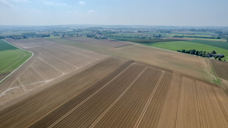 This aerial view showcases beautifully plowed farmland with vibrant patches of lush greenery in the backgroundの写真素材