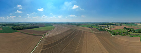 Fields and vast farms stretch out beneath a stunningly bright blue sky, showcasing the true beauty of agricultureの写真素材