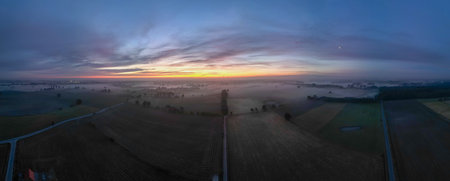 A stunning panoramic view of a breathtaking foggy landscape at dawn, beautifully showcasing natures charmの写真素材