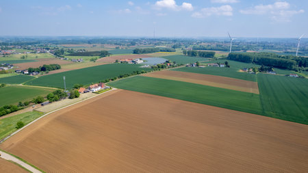 A breathtaking aerial perspective showcases the vibrant fields and extensive farmland beneath a clear blue skyの写真素材