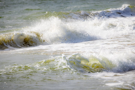 The beautiful ocean waves continuously rolling onto the sunlit shore capture the essence of coastal tranquilityの写真素材