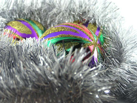 Three multi-coloured christmas spheres in a tinselの写真素材