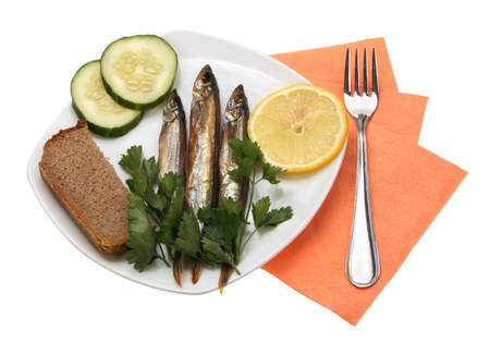 Smoked fishes with lemon, cucumber and green parsley on white plate. Close-up. Isolated on white background.の写真素材
