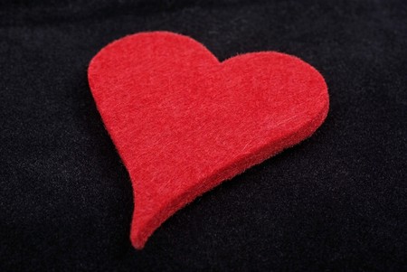 Close up of red heart isolated on black velvet background. Studio shot.の写真素材